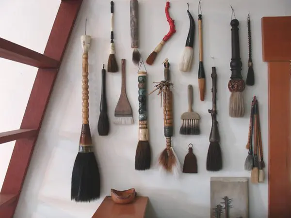 A wall with many different brushes hanging on it.