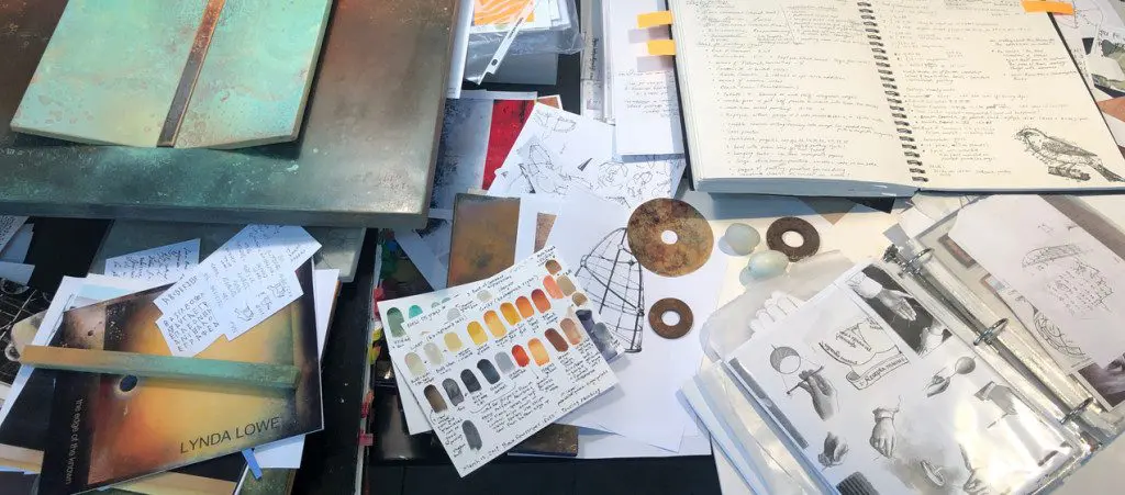 A table with papers and various art supplies.