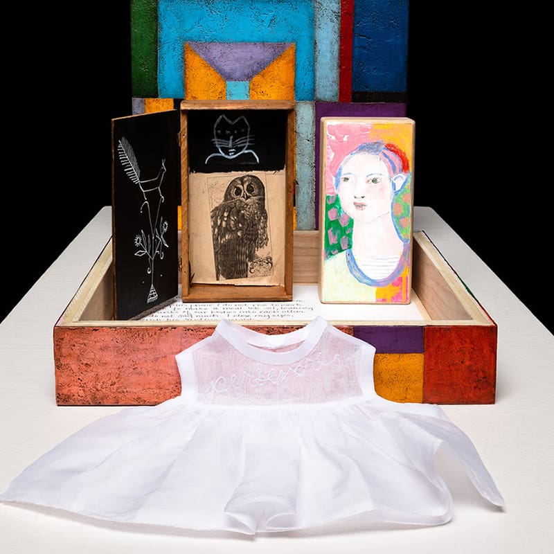A white dress and some paintings on display