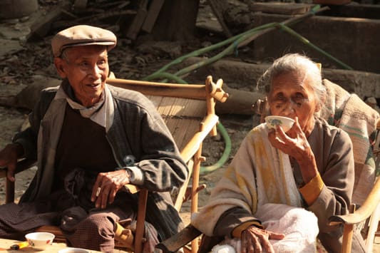 An old couple sitting in a chair outside