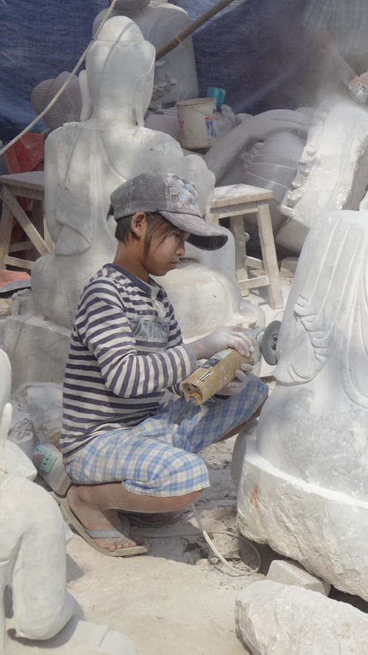 A boy is working on some sculptures