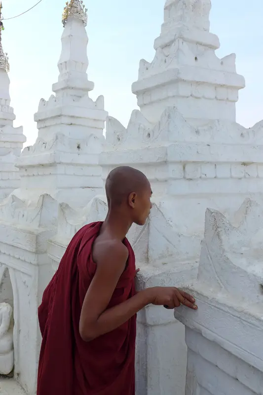 A monk standing in front of some white statues.