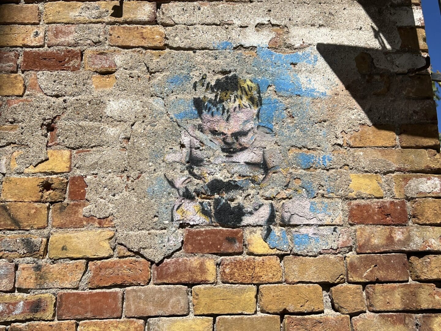 A painting of a child on a brick wall.